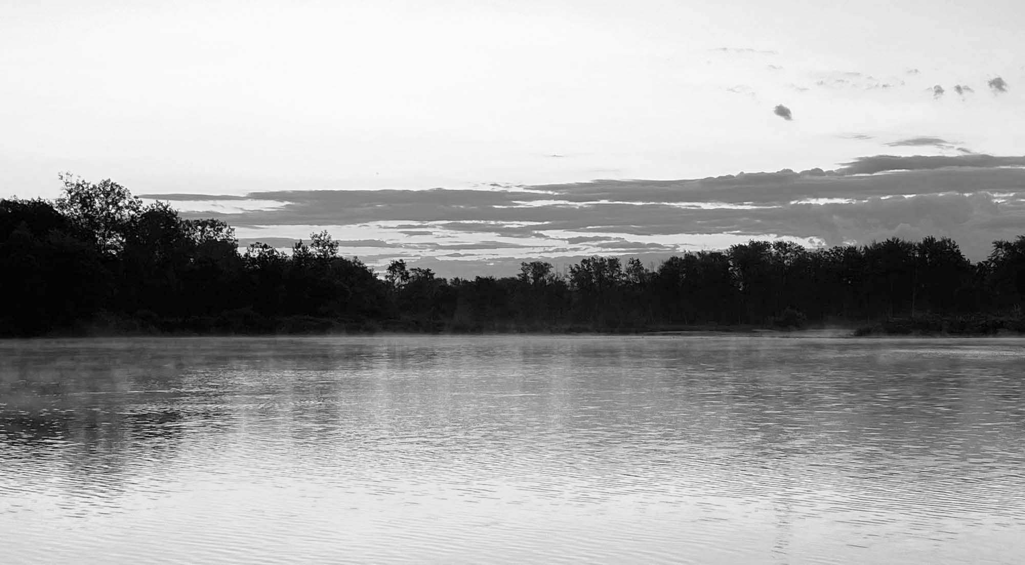 A calm lake at sunrise reflecting the shoreline